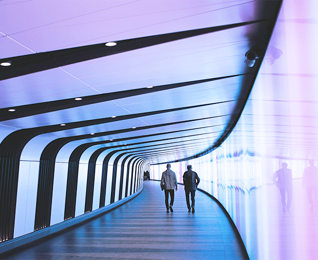 Image de personnes marchant dans un couloir coloré, illustrant l'innovation en recherche